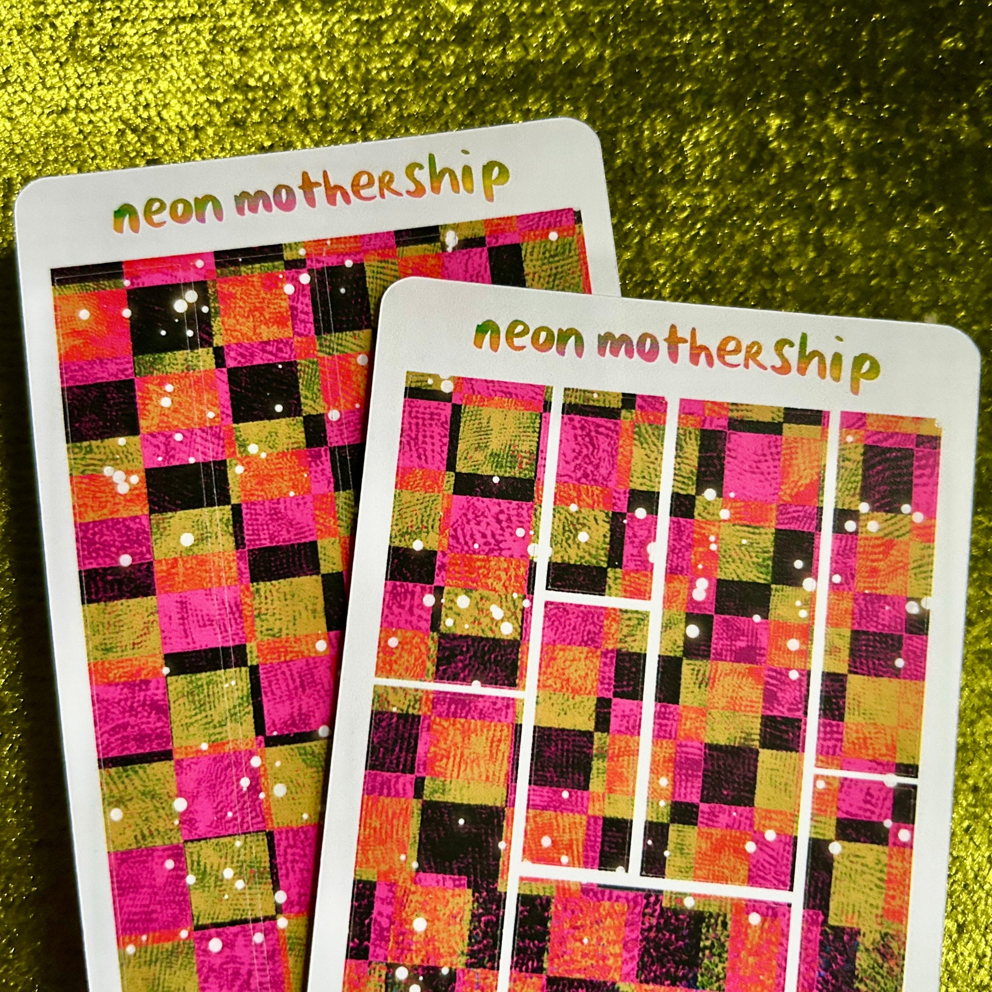 Two colorful checkered sticker sheets with 'neon mothership' branding on a green textured background.