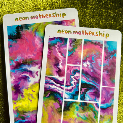 Colorful 'neon mothership' sticker sheets on a green textured surface