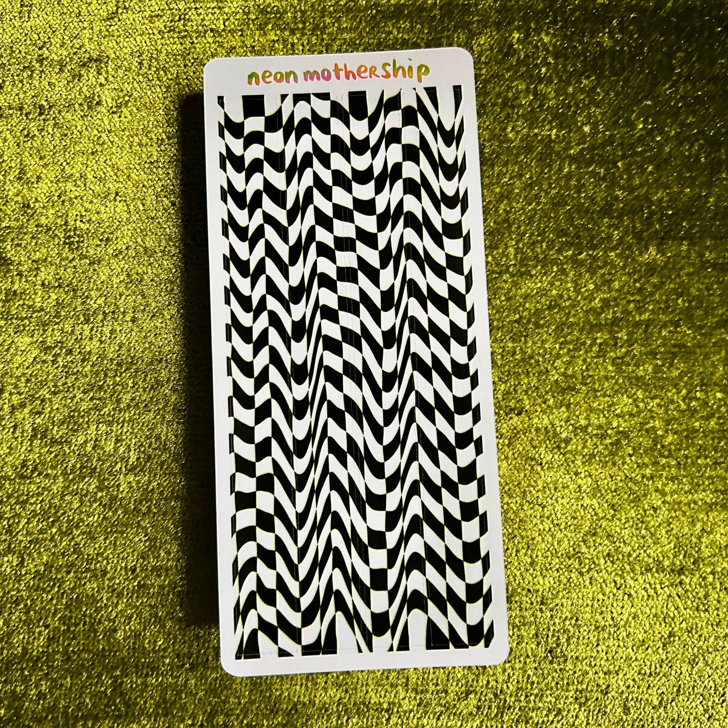 Black and white patterned sticker sheet with 'neon mothership' branding on a green textured background