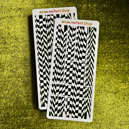 Two sticker sheets with black and white pattern on a green textured surface