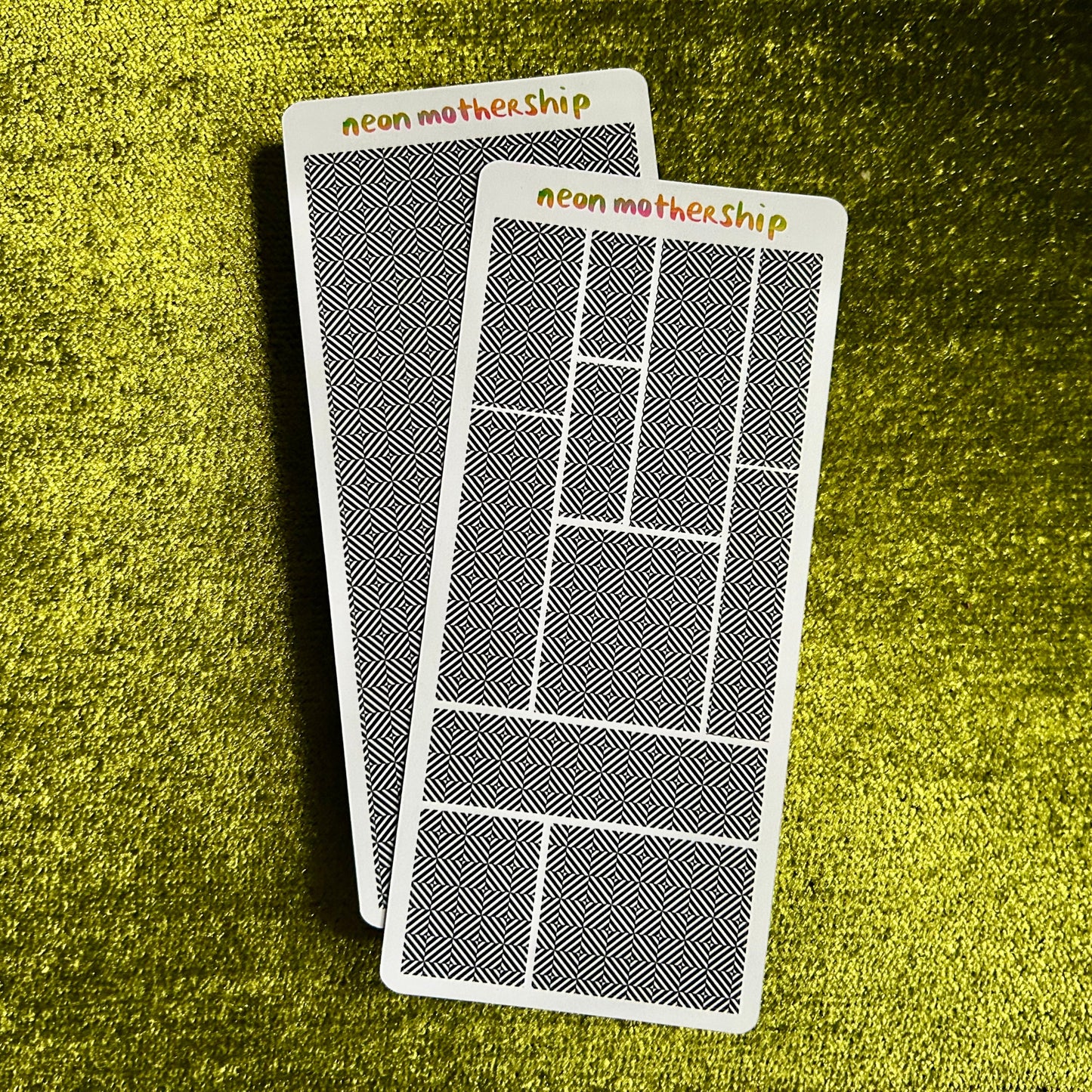Two sticker sheets with geometric designs and 'neon motherhip' text on a green textured surface.