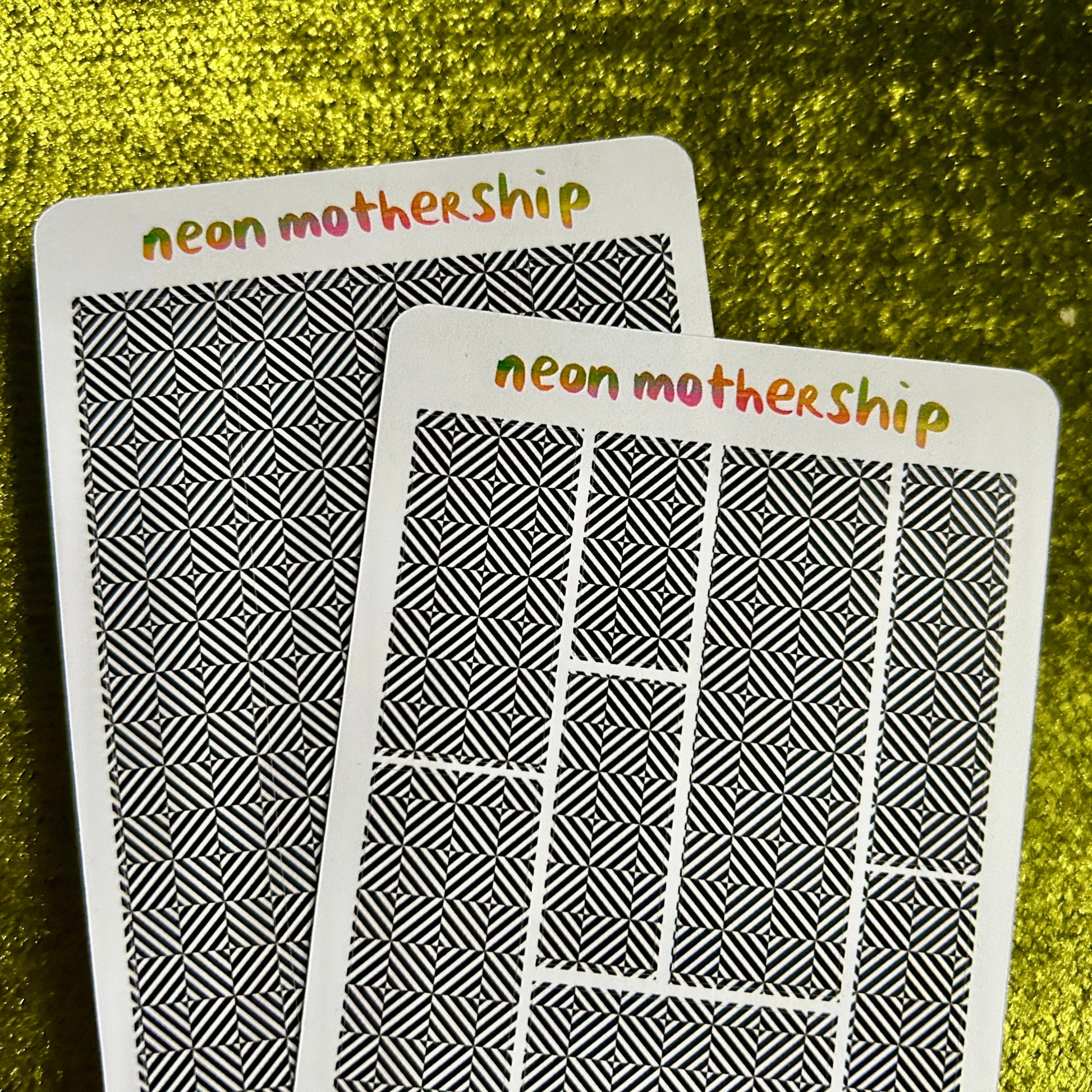 Two sticker sheets with 'neon mothership' text on a green textured background