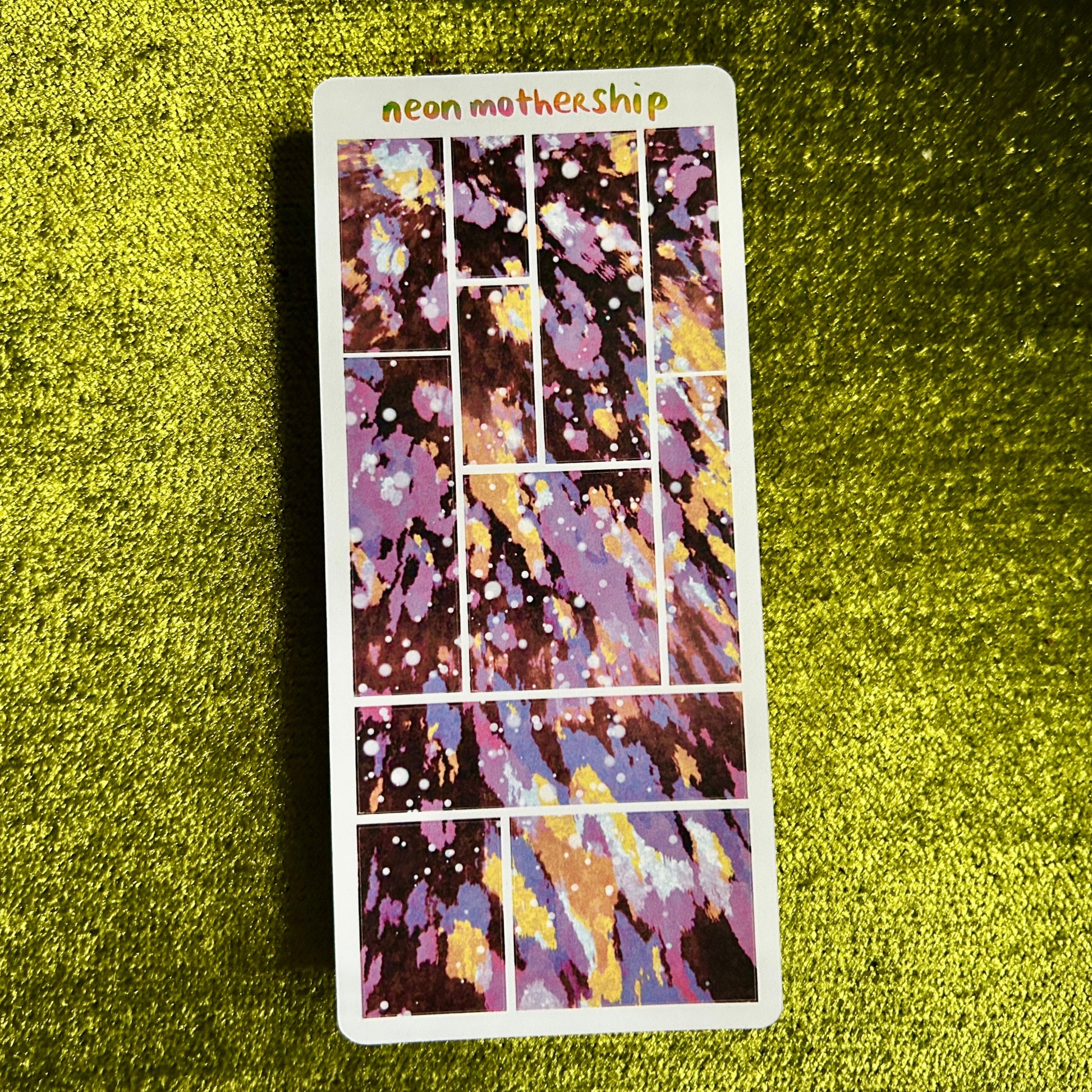 Colorful sticker sheet with 'neon mother ship' text on a green textured surface