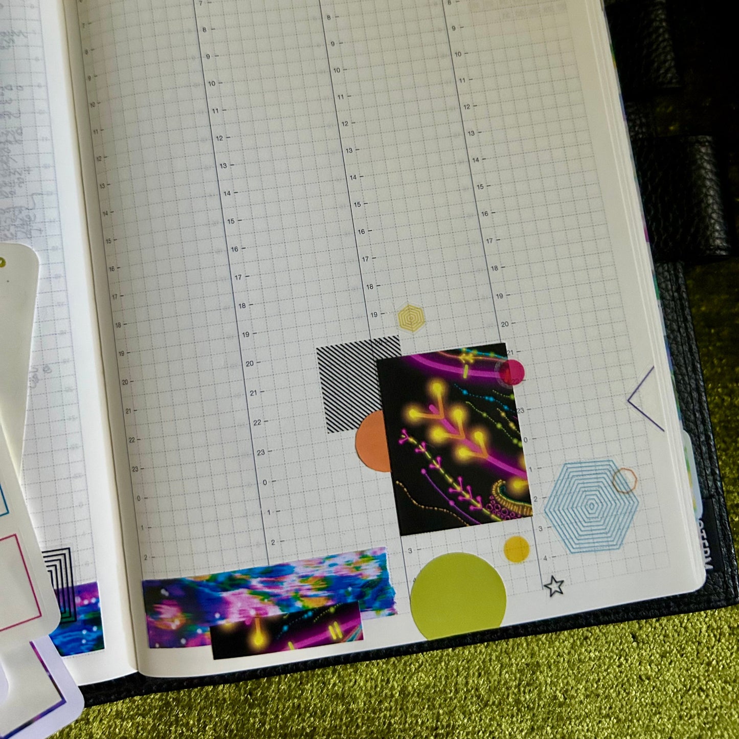 Open planner with colorful stickers on a green textured surface