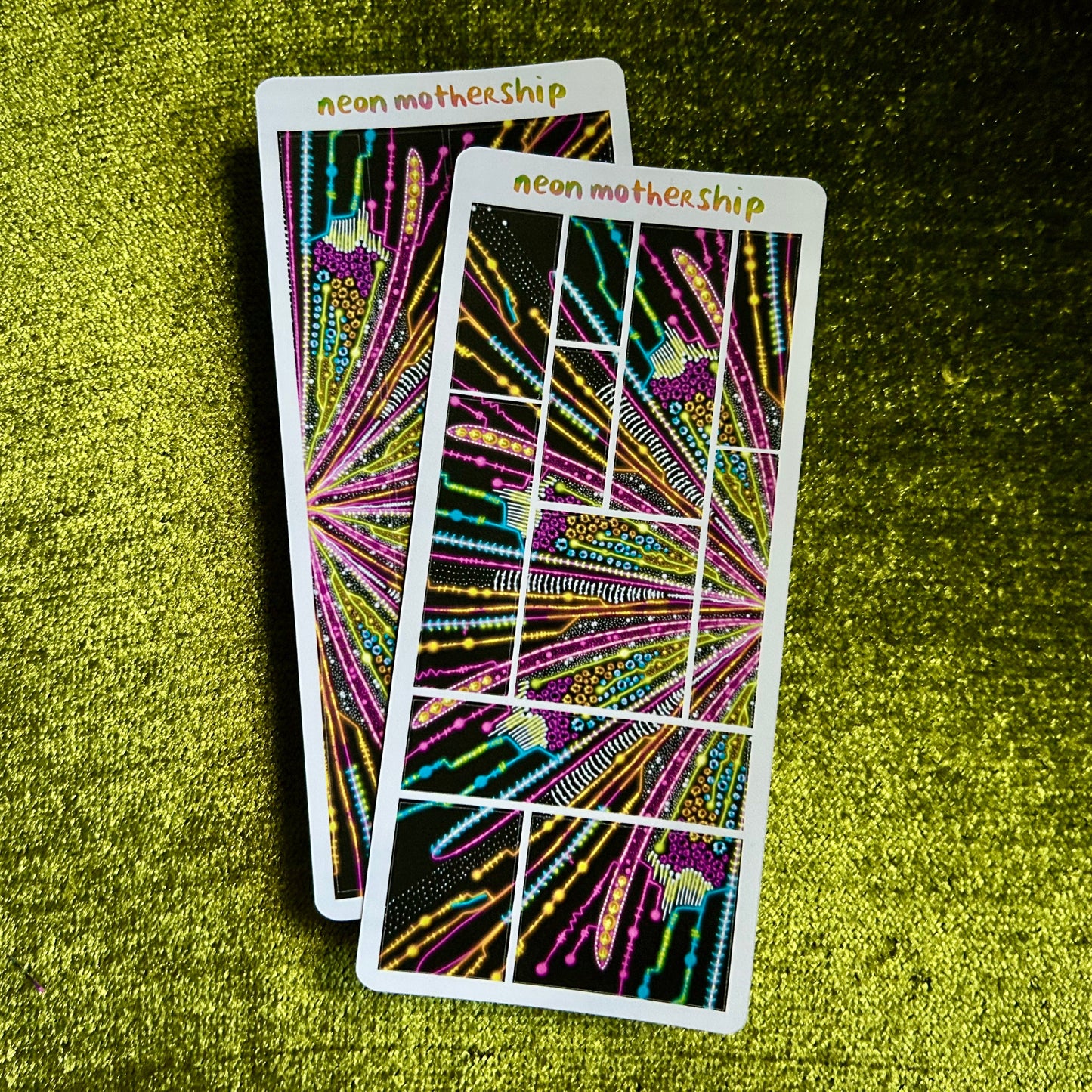 Two colorful sticker sheets with abstract designs on a green textured surface