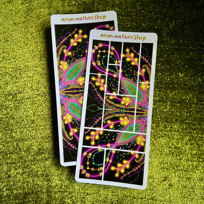 Two bright, glowing neon motherhip sticker sheets on a green textured surface
