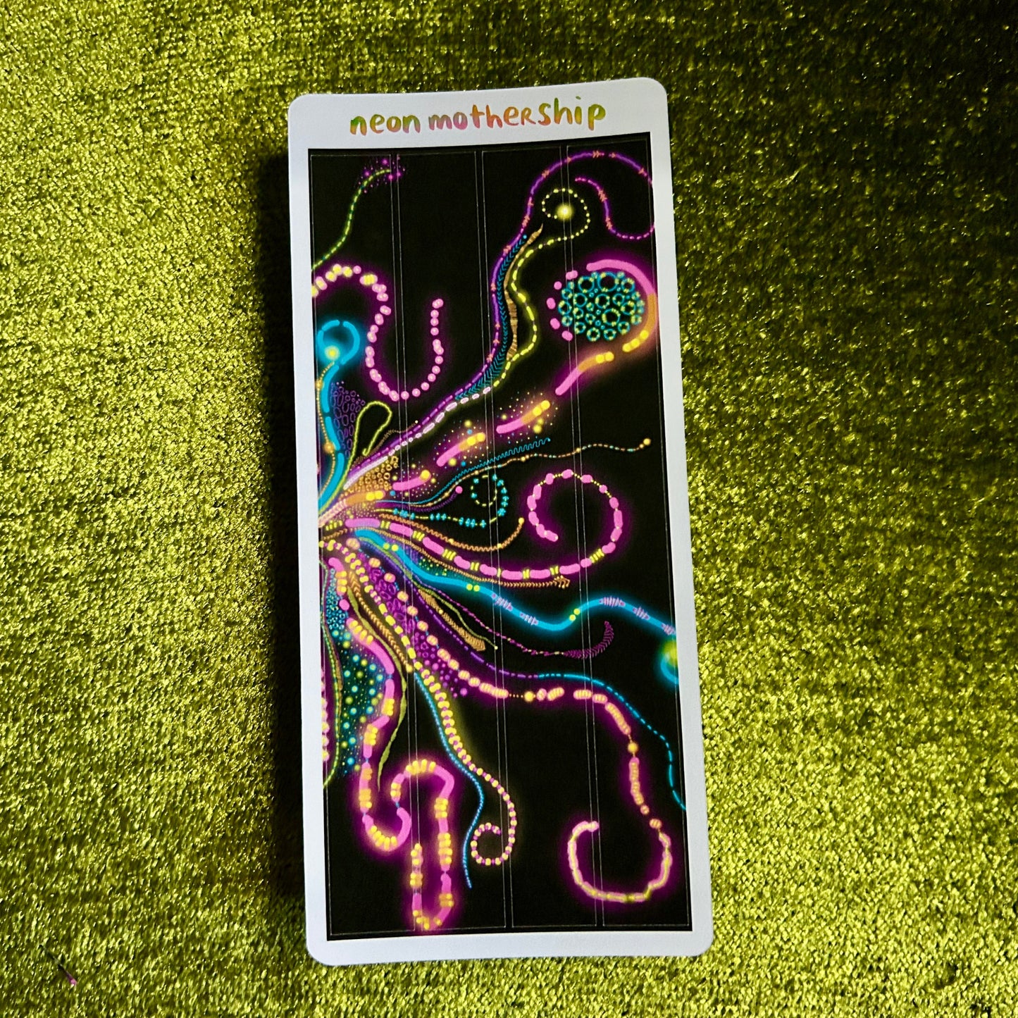 sticker sheet with neon MotherShip design on a green textured surface