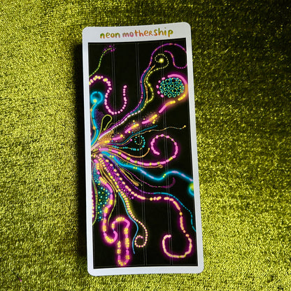 sticker sheet with neon MotherShip design on a green textured surface