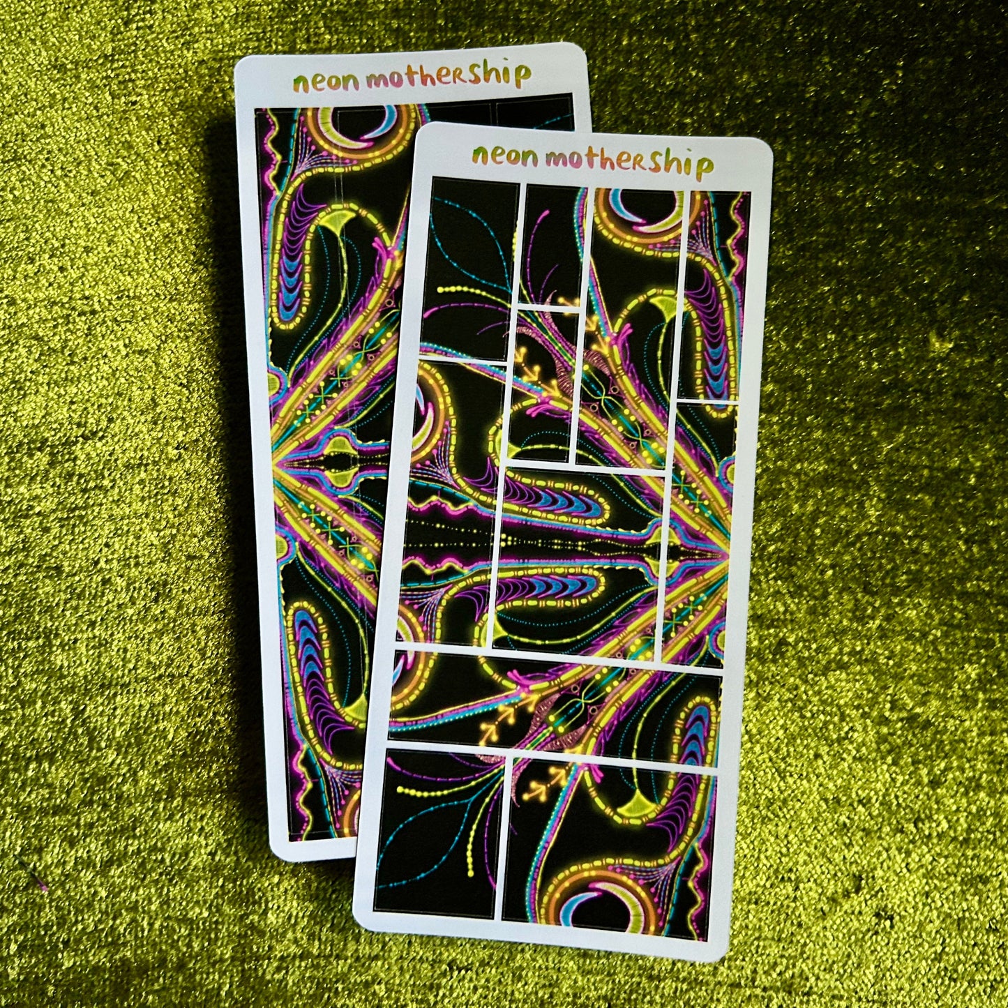 Two sticker sheets with abstract designs on a green textured surface