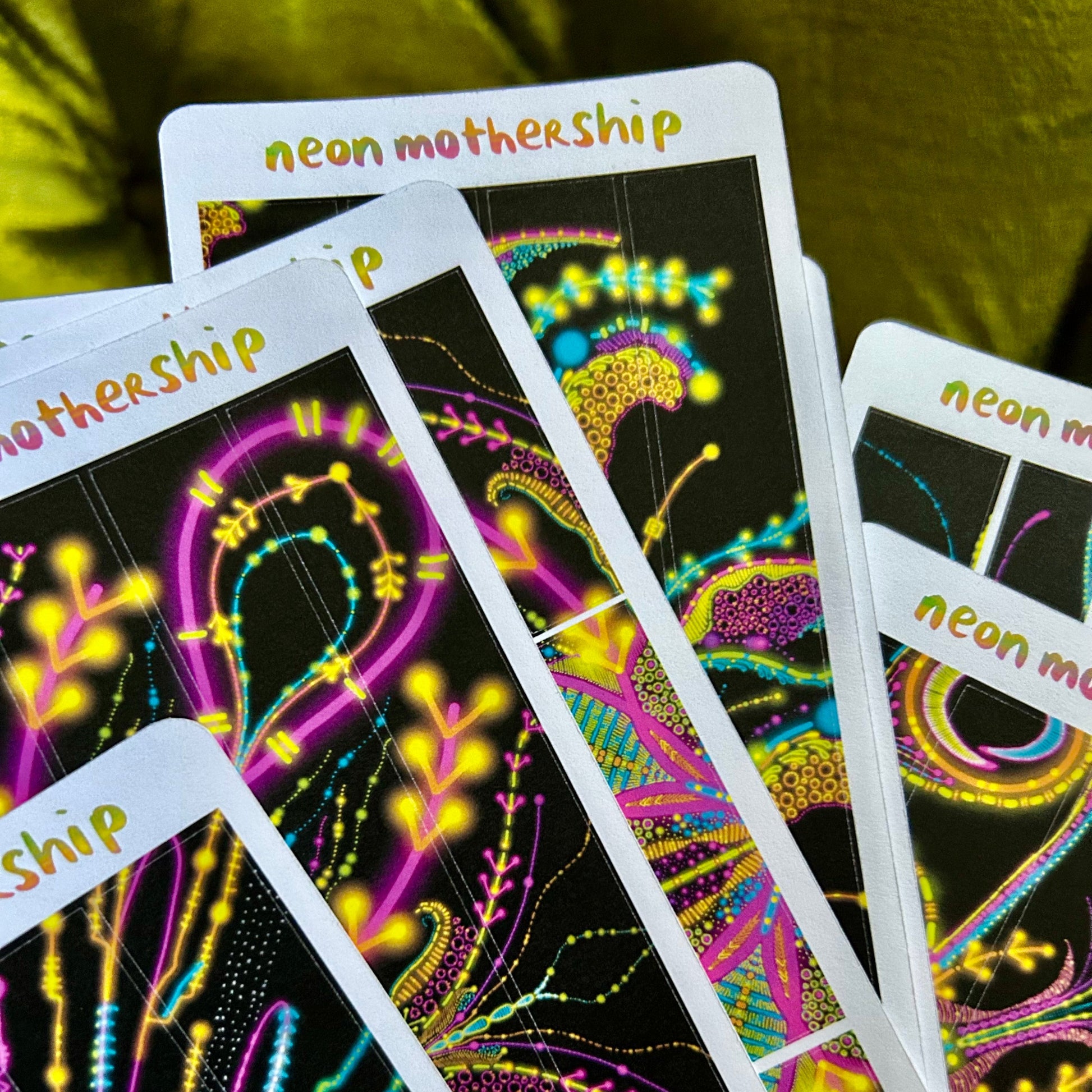 Neon MotherShip sticker sheets with colorful designs on a green background