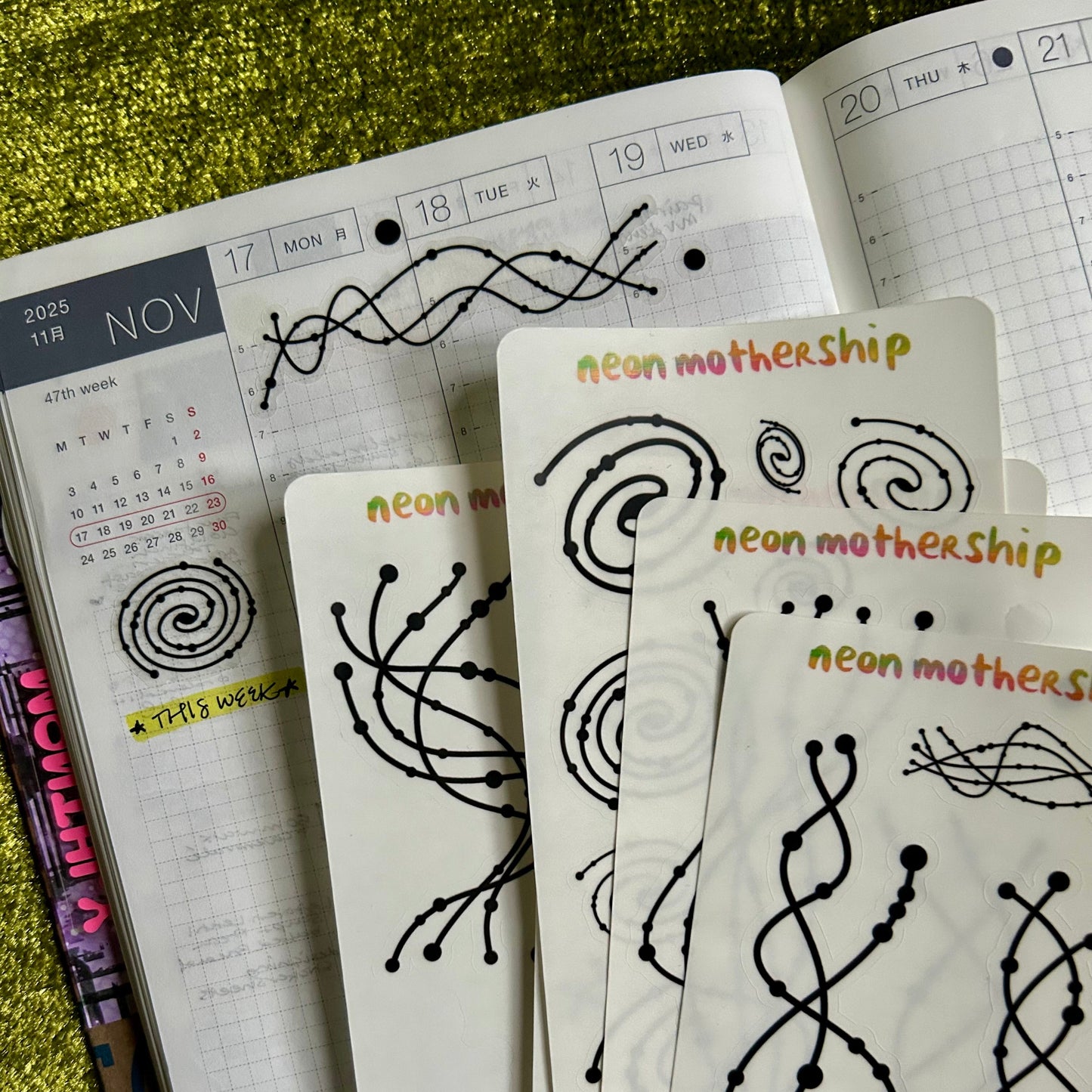 Sticker sheets with 'neon mothership' designs on a planner background
