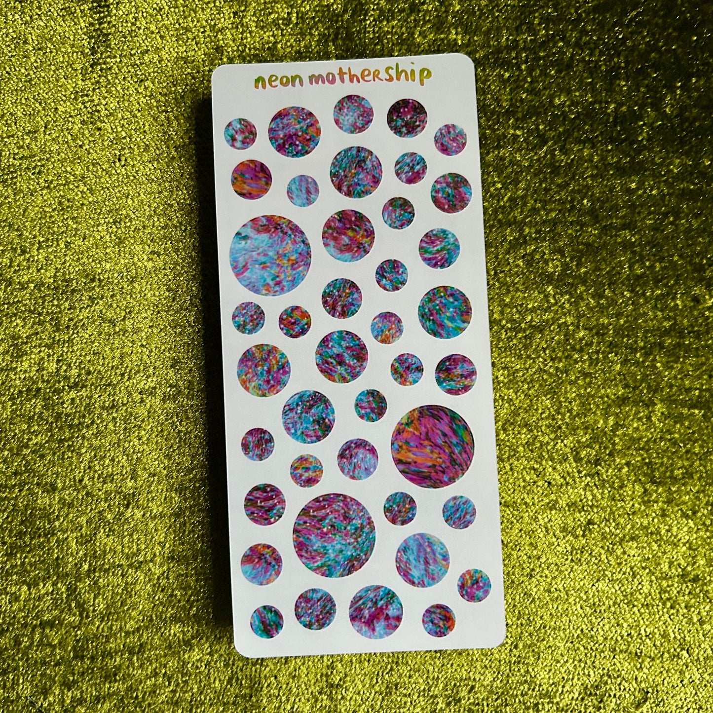 Sheet of colorful round stickers on a green textured background