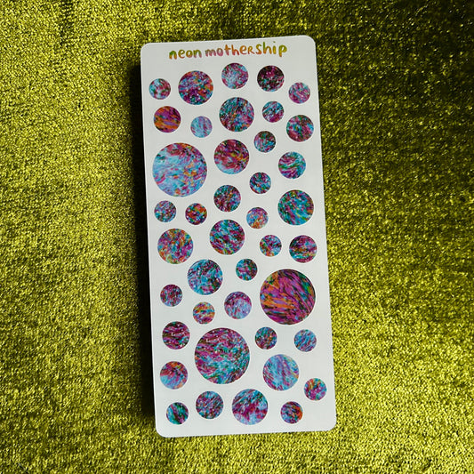 Sheet of colorful round stickers on a green textured background