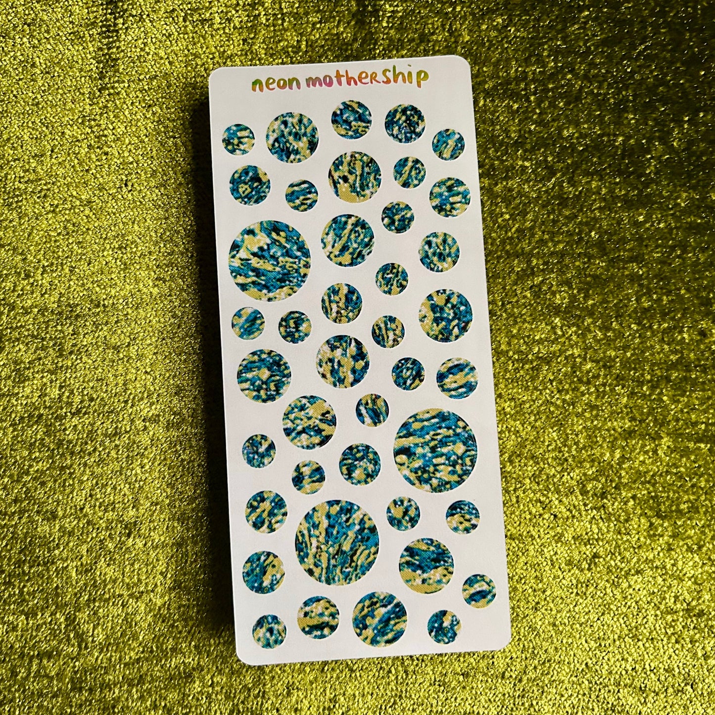 Sheet of round, multicolored stickers on a green textured background
