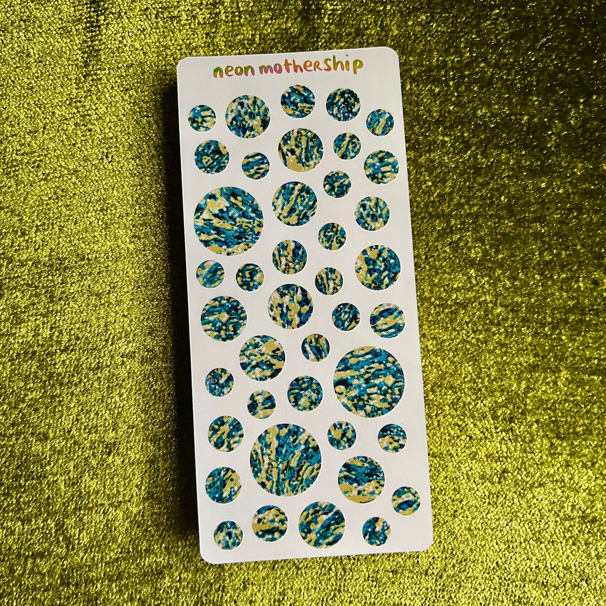 Sheet of round, multicolored stickers on a green textured background