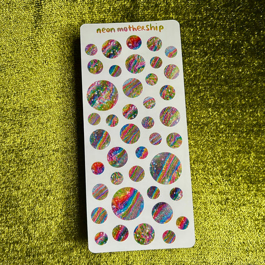 Sheet of colorful round stickers on a green glittery background