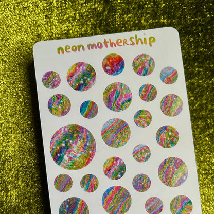 Sheet of colorful round stickers with 'neon mothership' branding on a glittery green background.