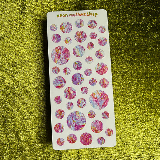 Sheet of colorful circular stickers on a green textured surface
