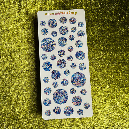 Sheet of blue and purple marbled stickers on a green textured surface