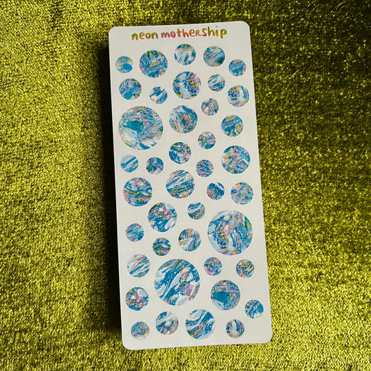 Sheet of round, multicolored stickers on a green textured surface with 'neon mothership' branding.