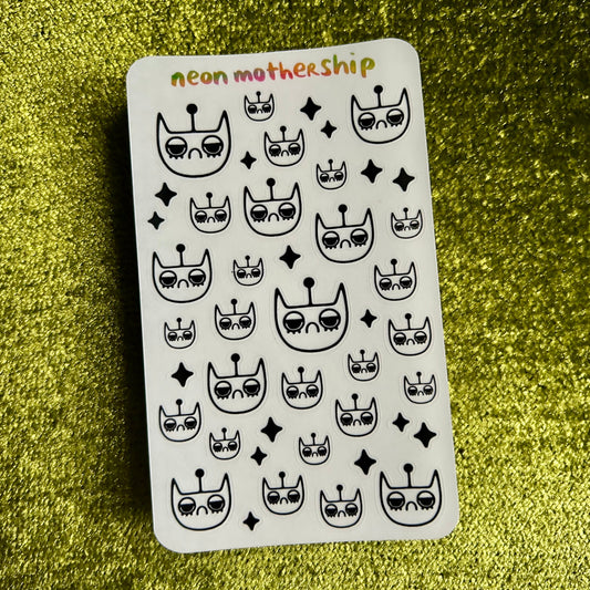 Sheet of black and white cat-themed stickers on a green glittery background
