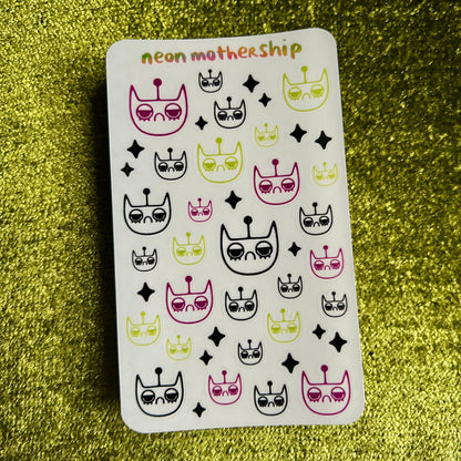 Sheet of stickers with cat-themed designs on a green textured background
