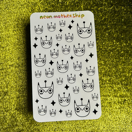 Sticker sheet with black and white cat designs on a green textured surface