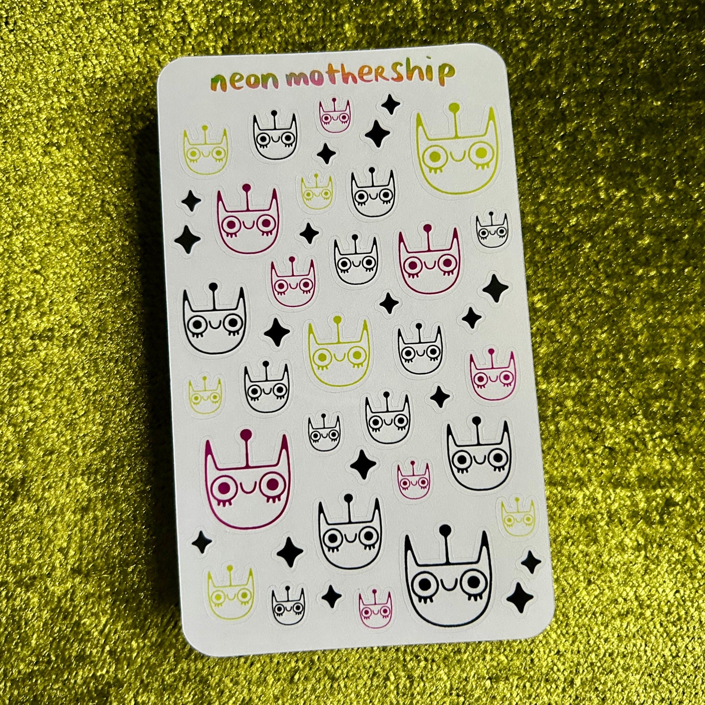 Card with neon motherhip spacecat design on a green textured surface
