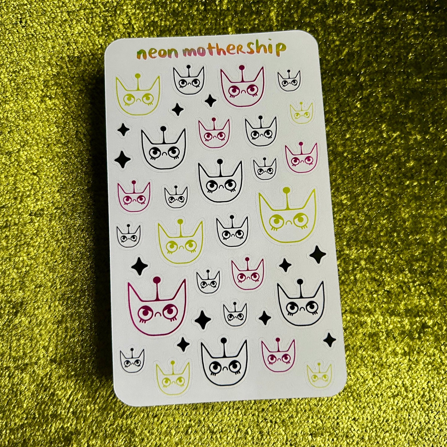 Sheet of nail art stickers with various designs on a green textured background
