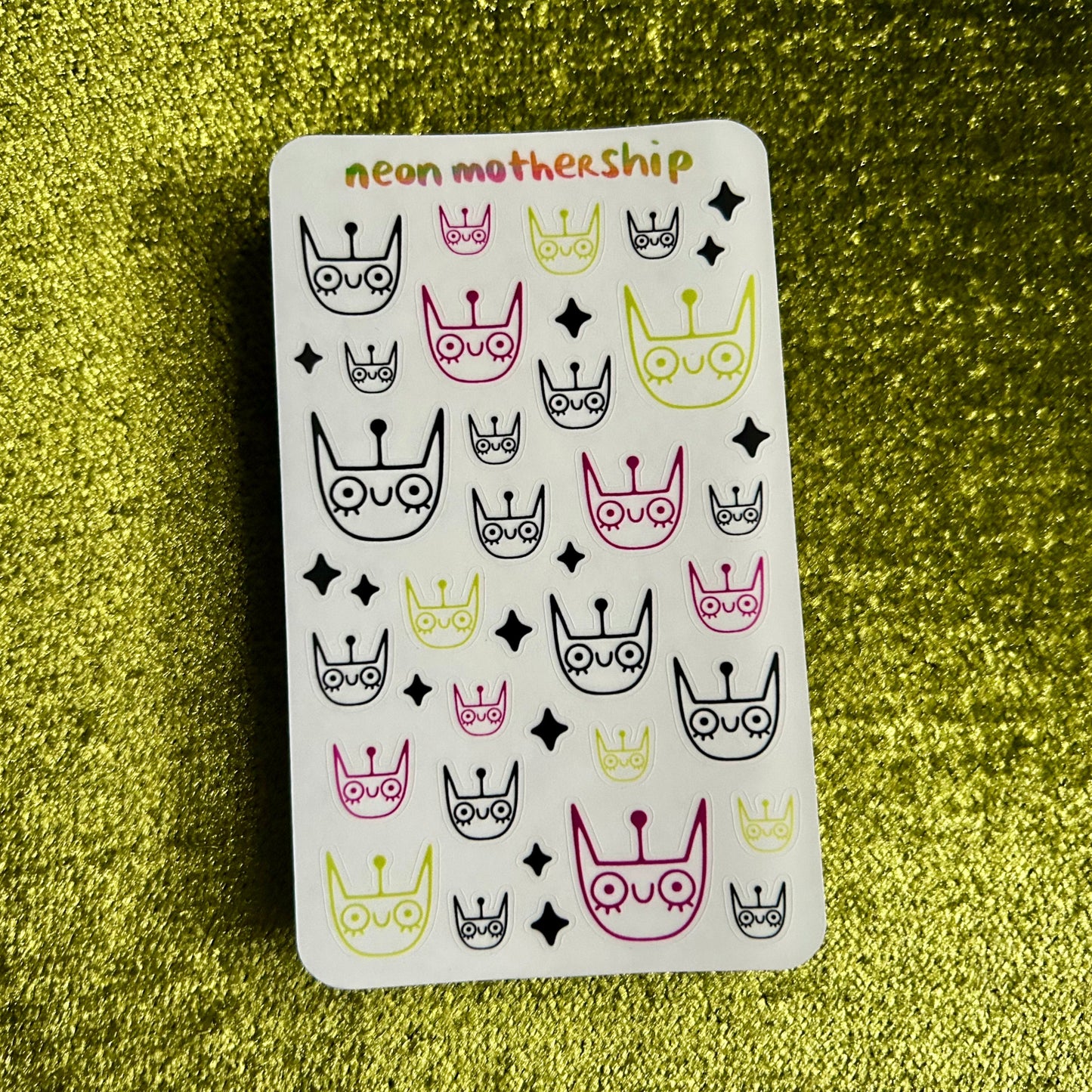 Sheet of neon motherhood stickers on a green glittery background