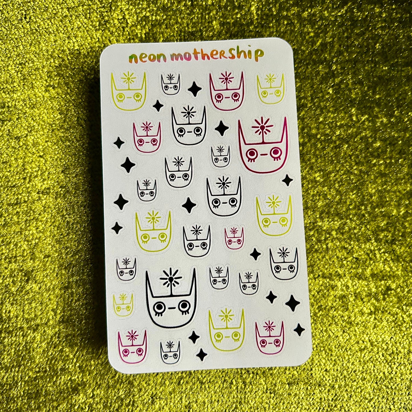 sticker sheet with cat-themed design on a green textured surface