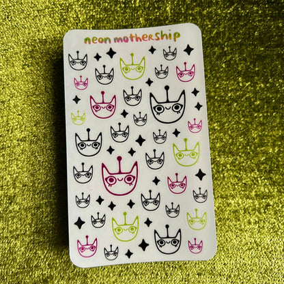 Sheet of stickers with cat and crown designs on a green textured background