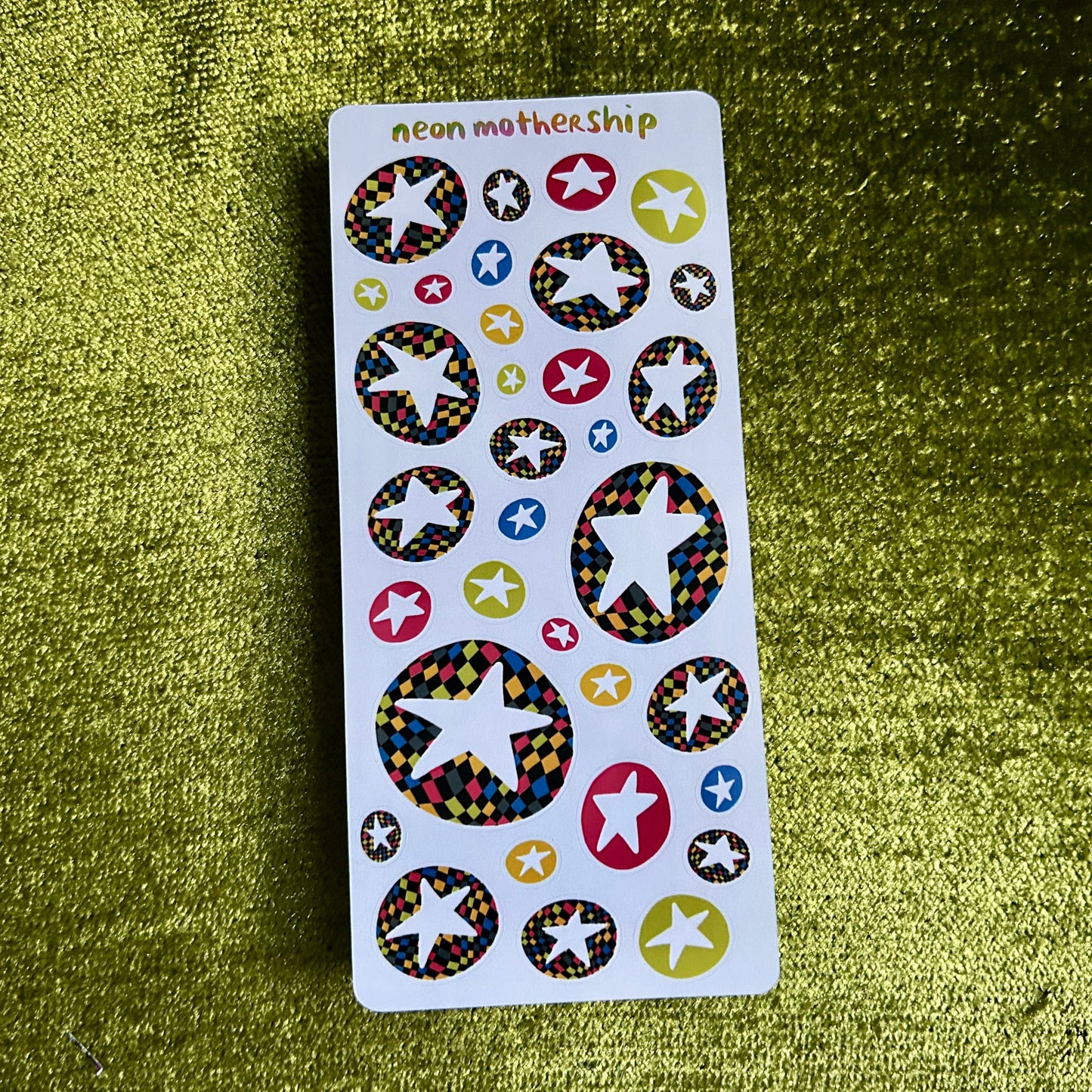 Sheet of colorful star-shaped stickers on a green textured background