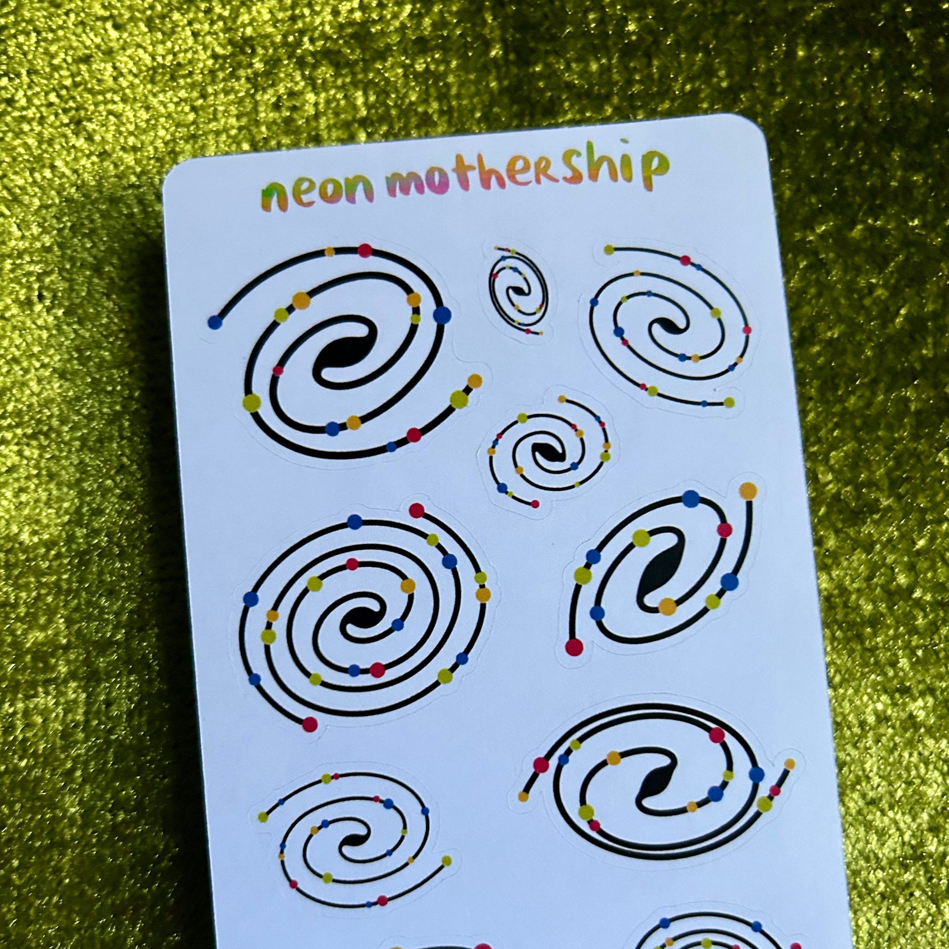 Sheet of stickers with spiral designs on a green textured background