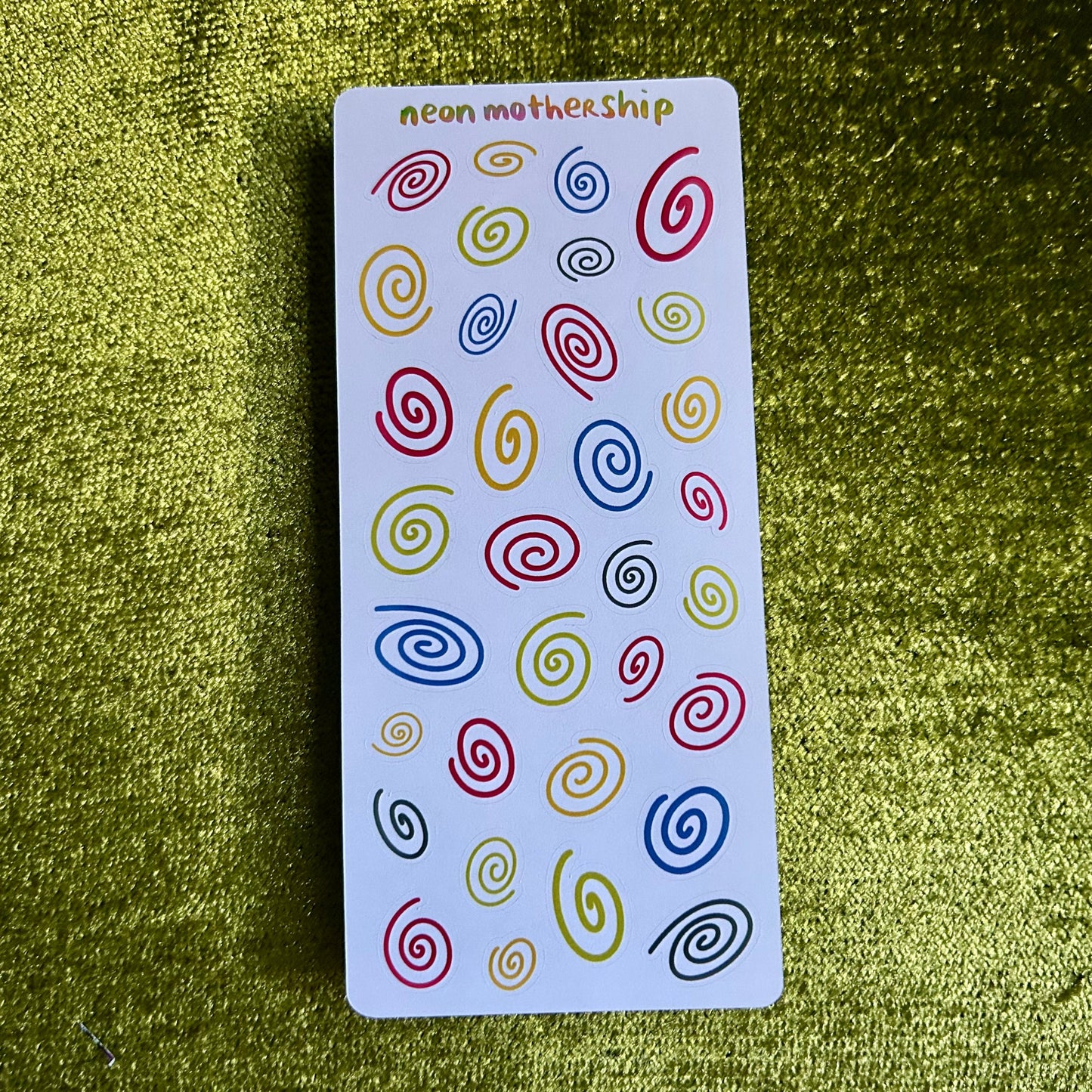 sticker sheet with colorful spiral patterns on a green textured surface