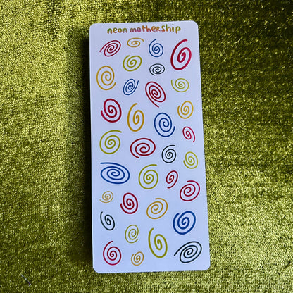 sticker sheet with colorful spiral patterns on a green textured surface