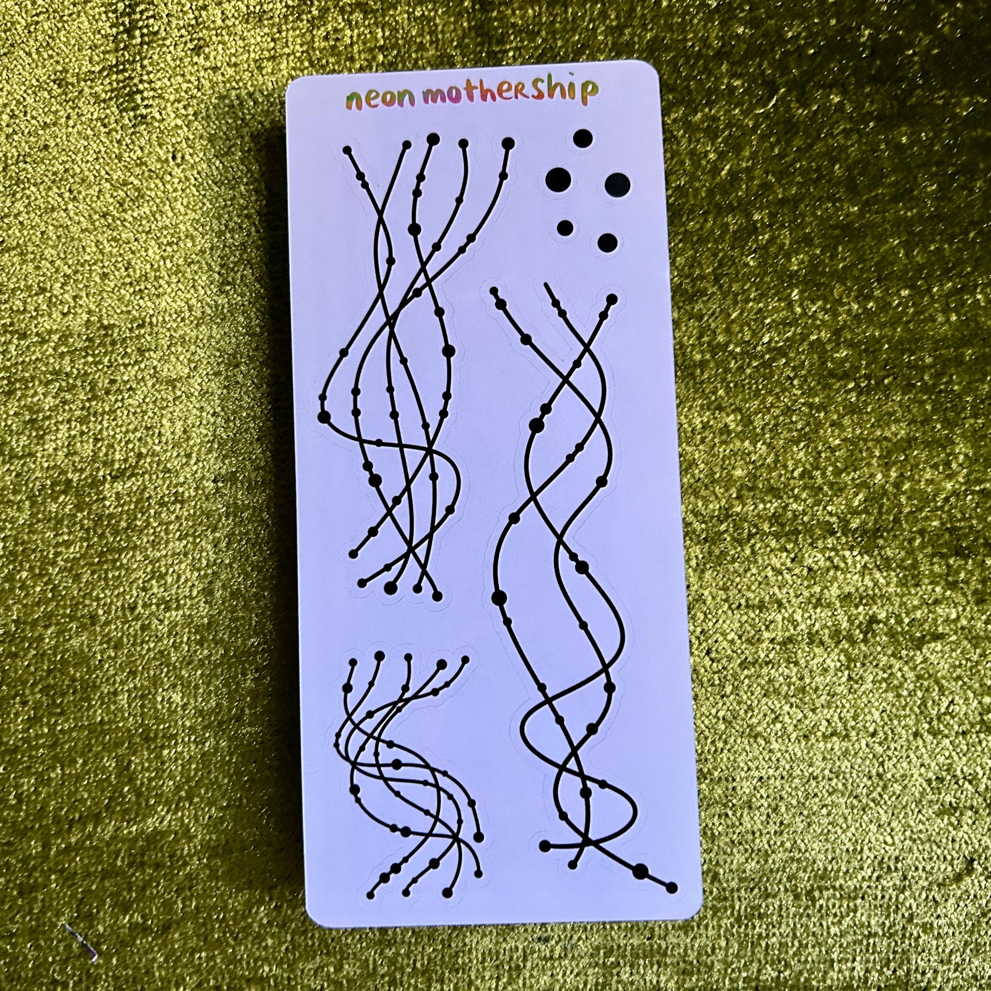Rectangular card with black line art on a purple background, featuring the text 'neon mothership' on a green textured surface.