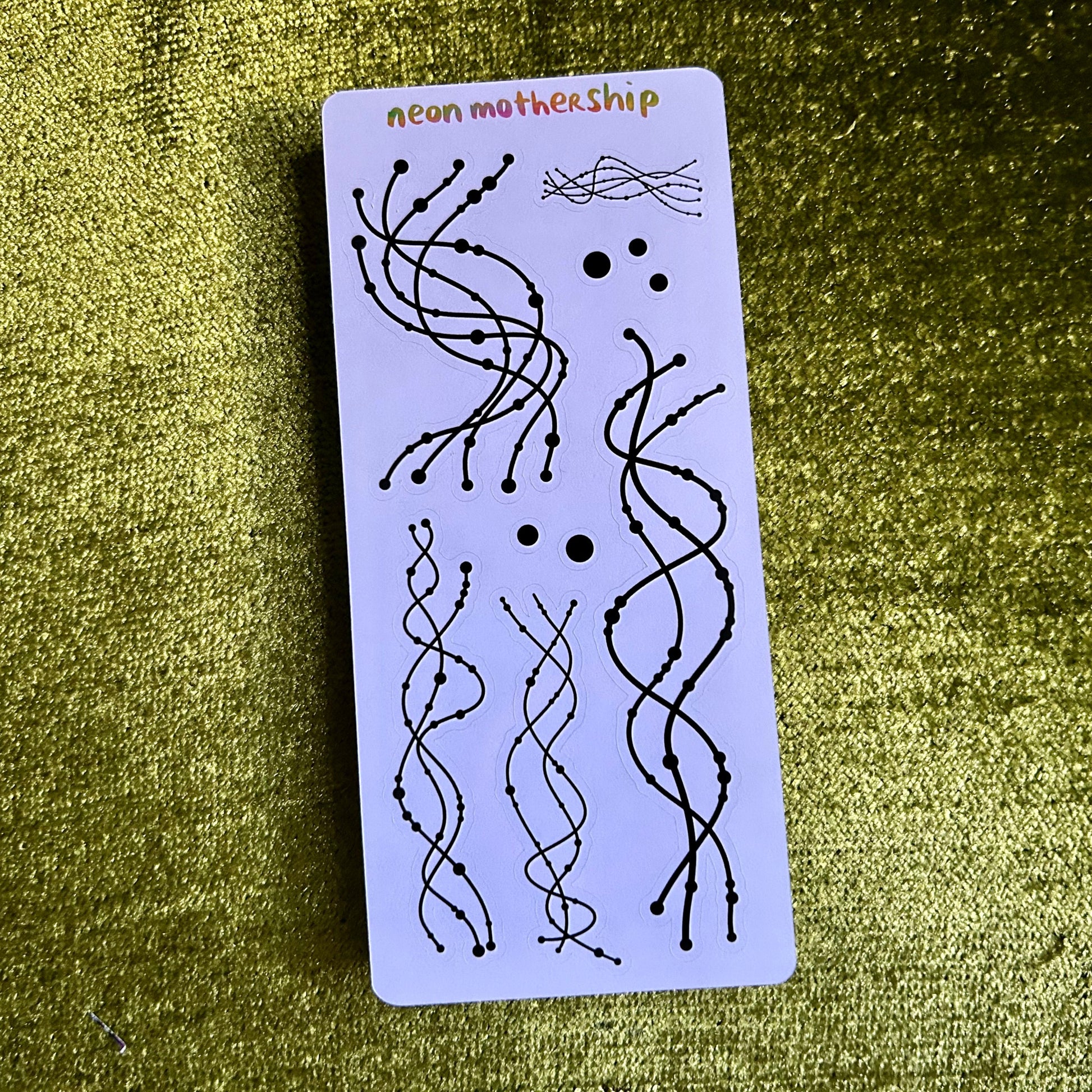 sticker sheet with black wavy line art designs on a green textured surface
