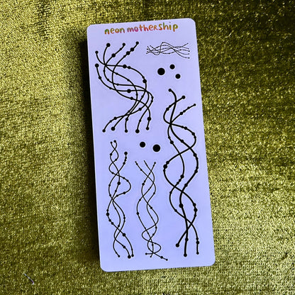sticker sheet with black wavy line art designs on a green textured surface