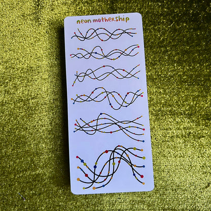 sticker sheet with wavy lines and colorful beads on a green textured surface