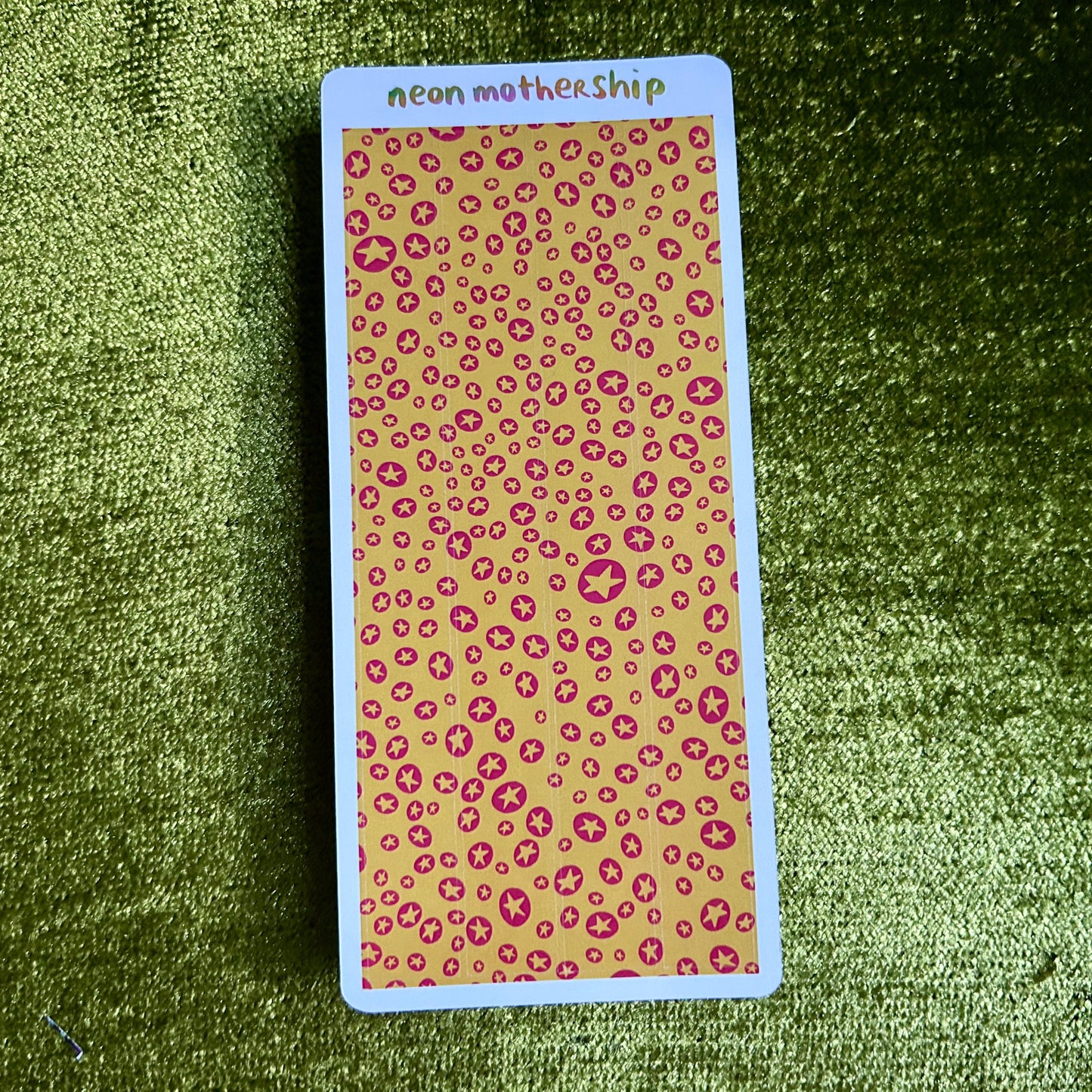Card with pink star print pattern on a green textured surface