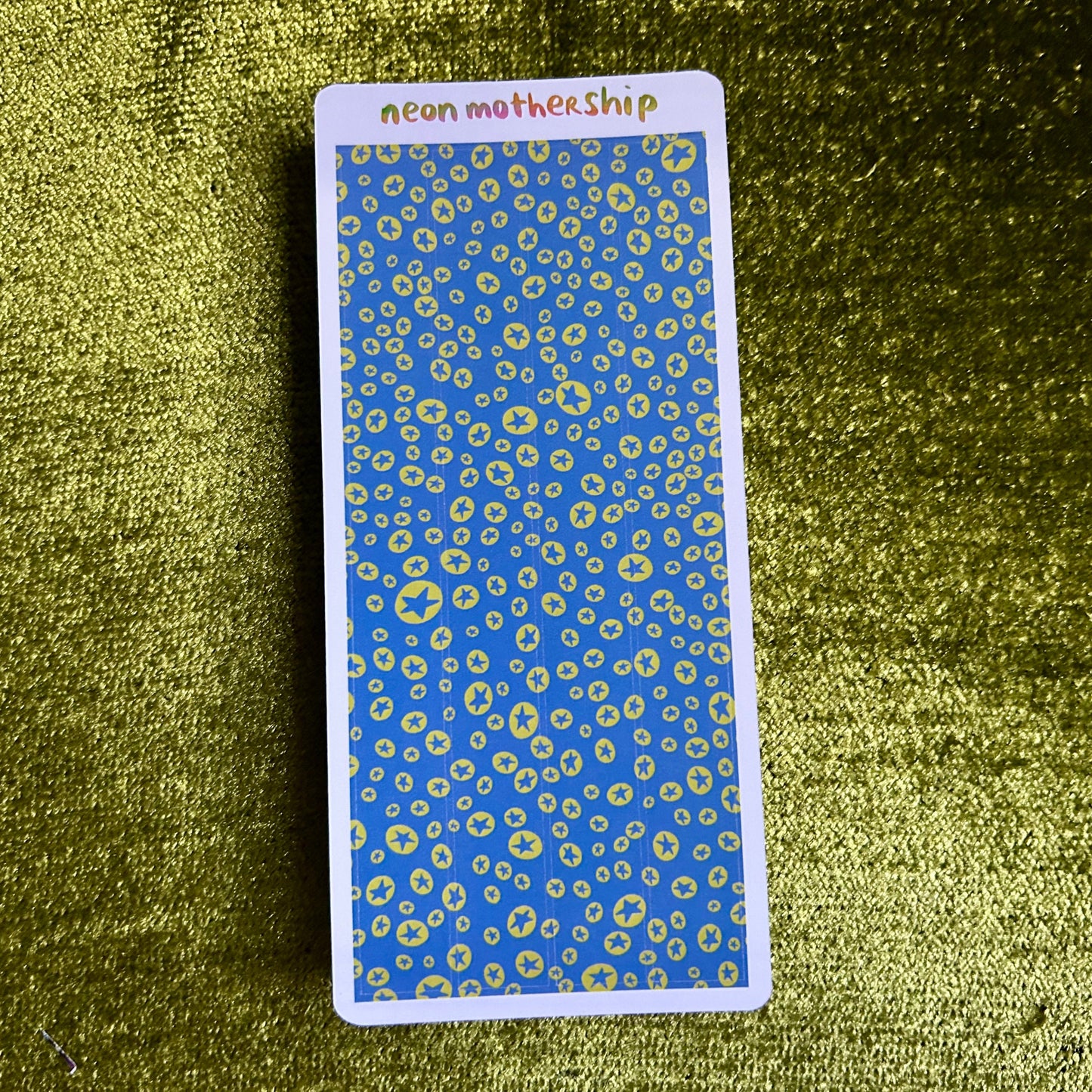 Rectangular card with blue and green pattern on a textured green surface