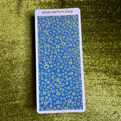 Rectangular card with blue and green pattern on a textured green surface