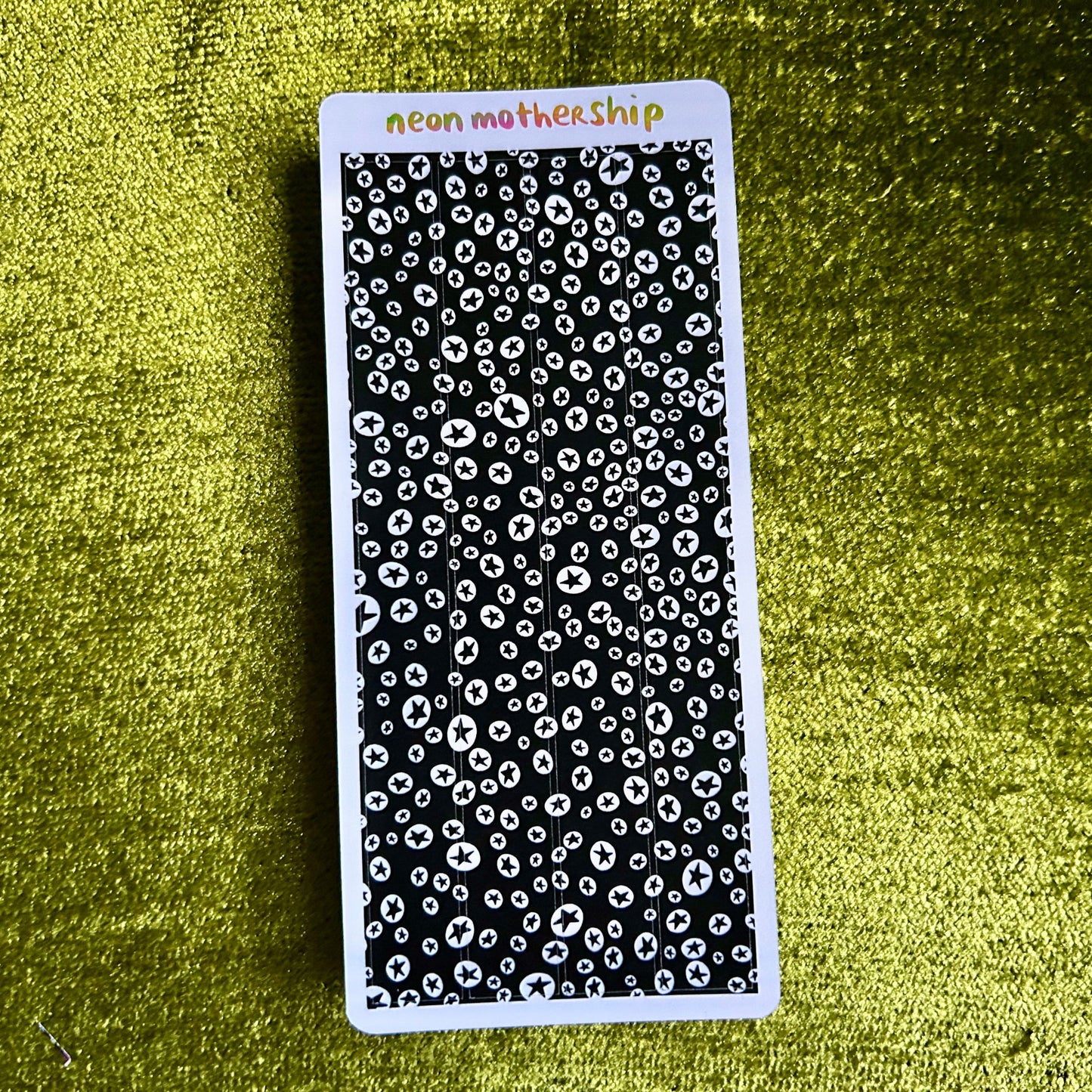 Black and white patterned sticker sheet with 'neon motherShip' branding on a green textured background