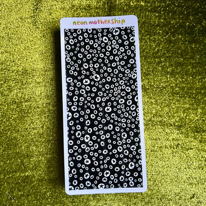 Black and white patterned sticker sheet with 'neon motherShip' branding on a green textured background