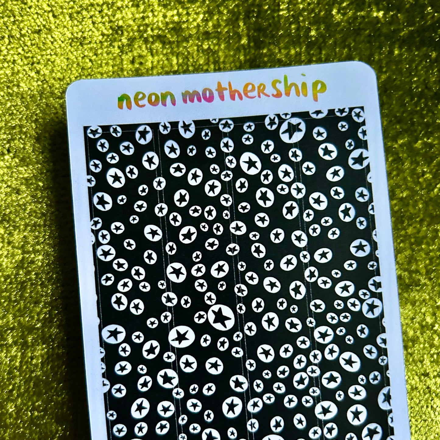 sticker sheet with black and white pattern and 'neon mothership' text on a green textured background