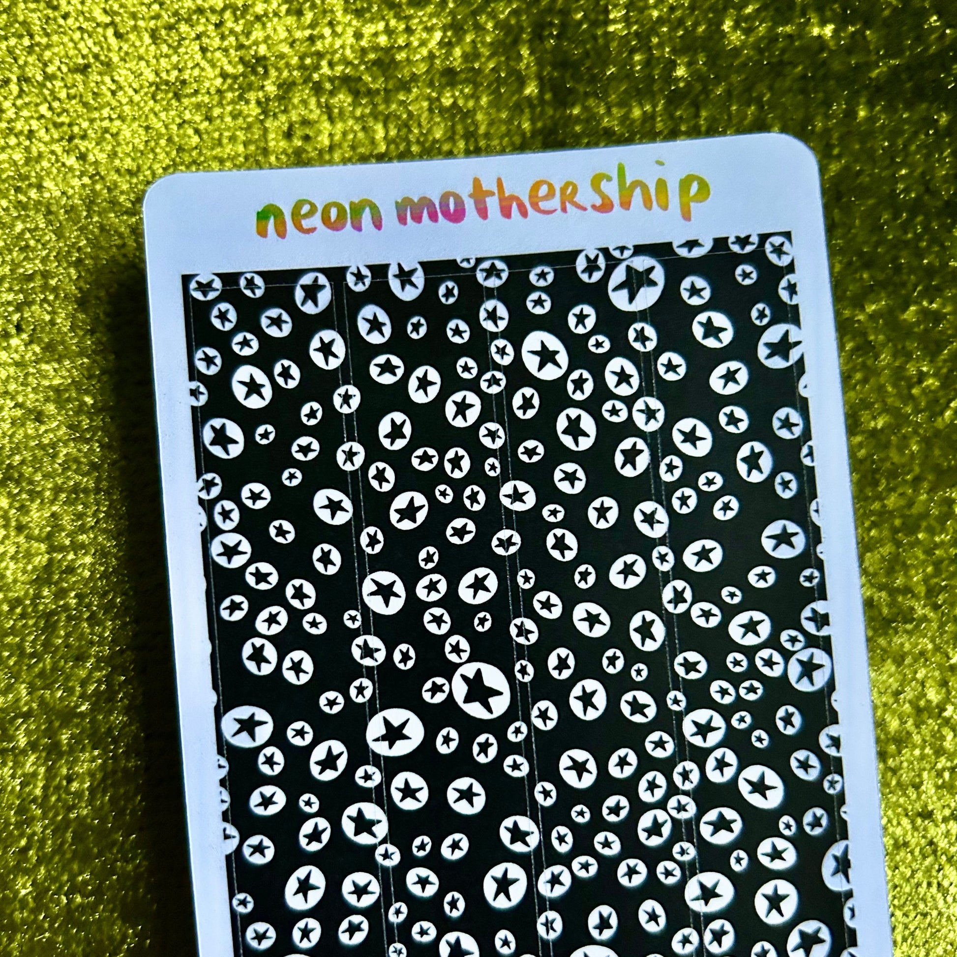 sticker sheet with black and white pattern and 'neon mothership' text on a green textured background