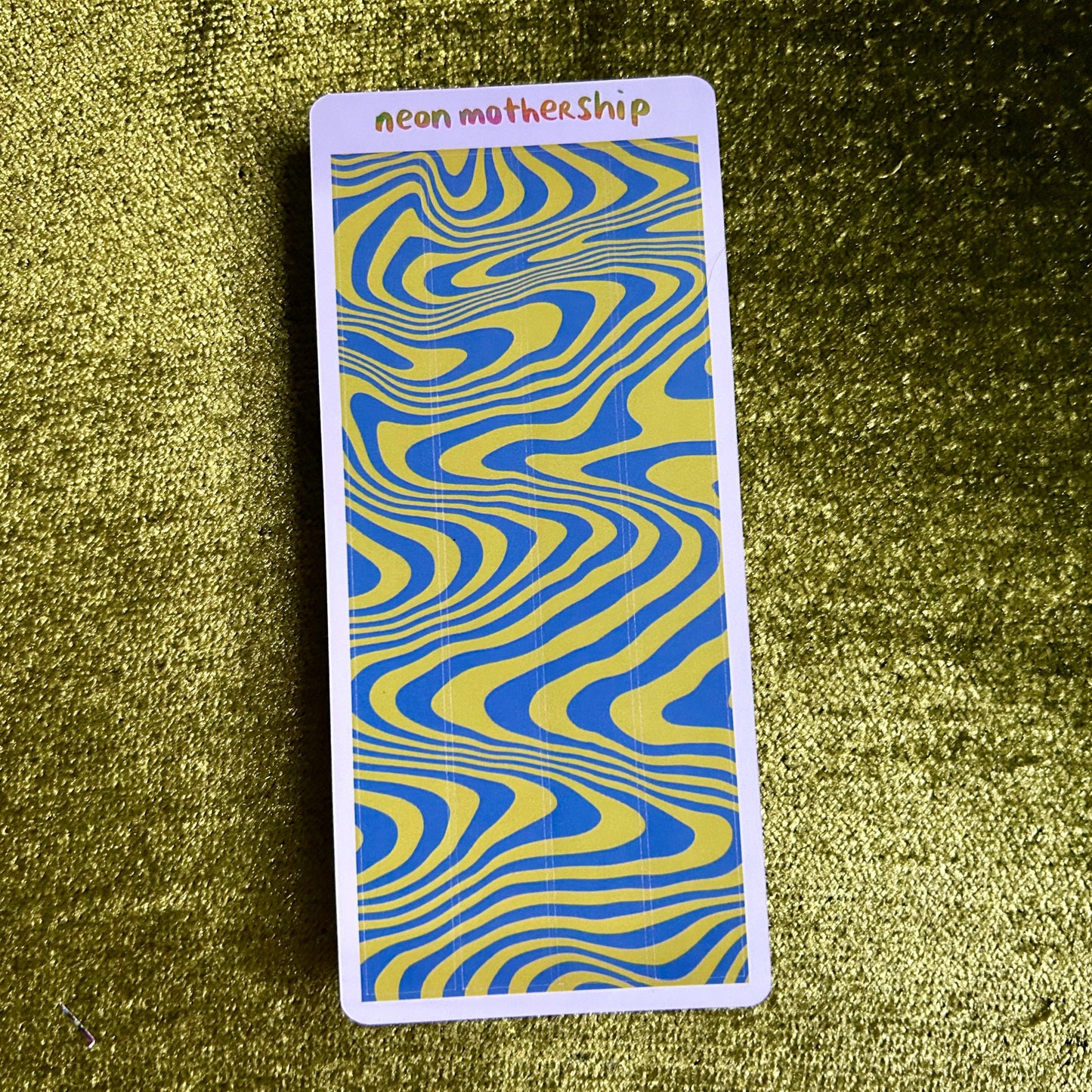 sticker sheet with blue and yellow wavy pattern on a textured green surface