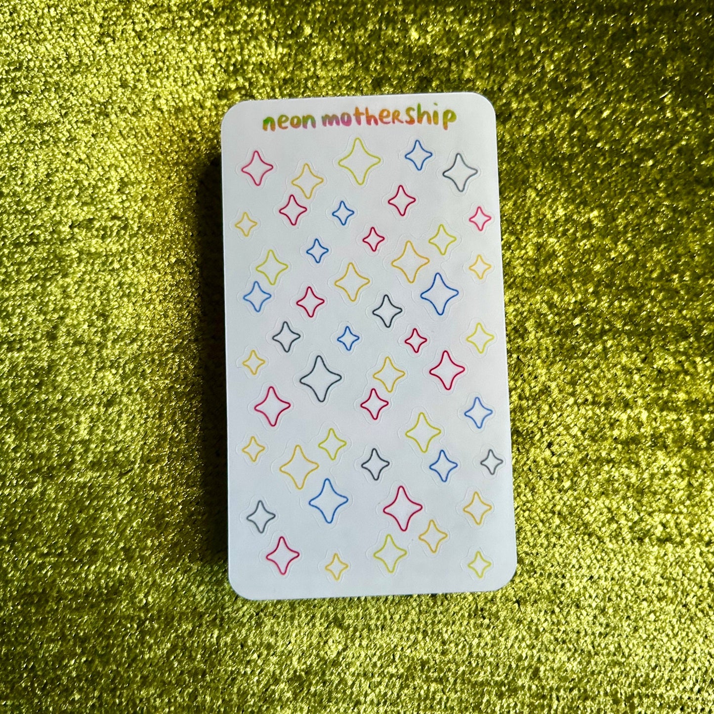 small sticker sheet with colorful star patterns on a green textured surface