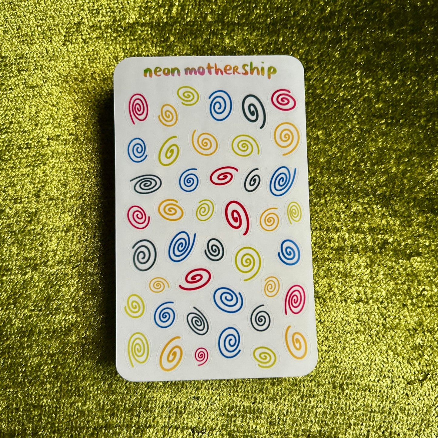 sticker sheet with colorful spiral patterns on a green textured background